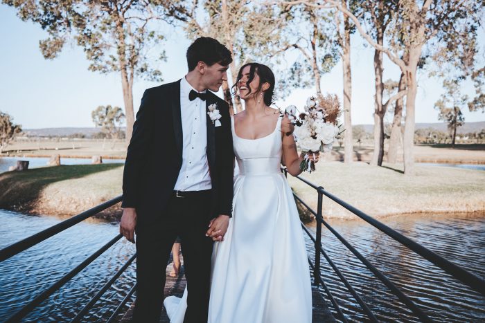 Groom Walking with Bride Wearing Modern Satin Wedding Gown by Maggie Sottero at Vineyard Wedding