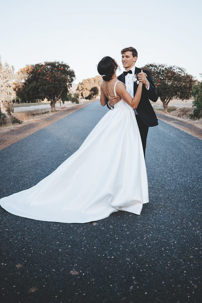 Groom Dancing with Bride Wearing Modern Satin Wedding Dress Called Selena by Maggie Sottero