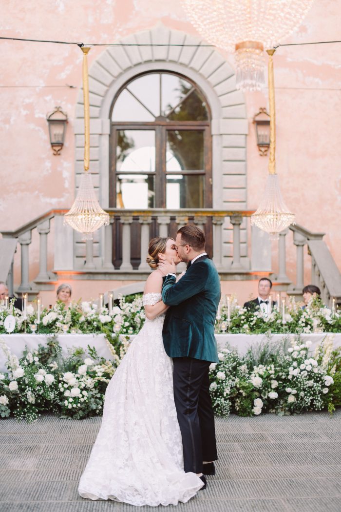Bride kissing her groom wearing Alessandra by Maggie Sottero while he wears a blue suit as his something blue wedding tradition