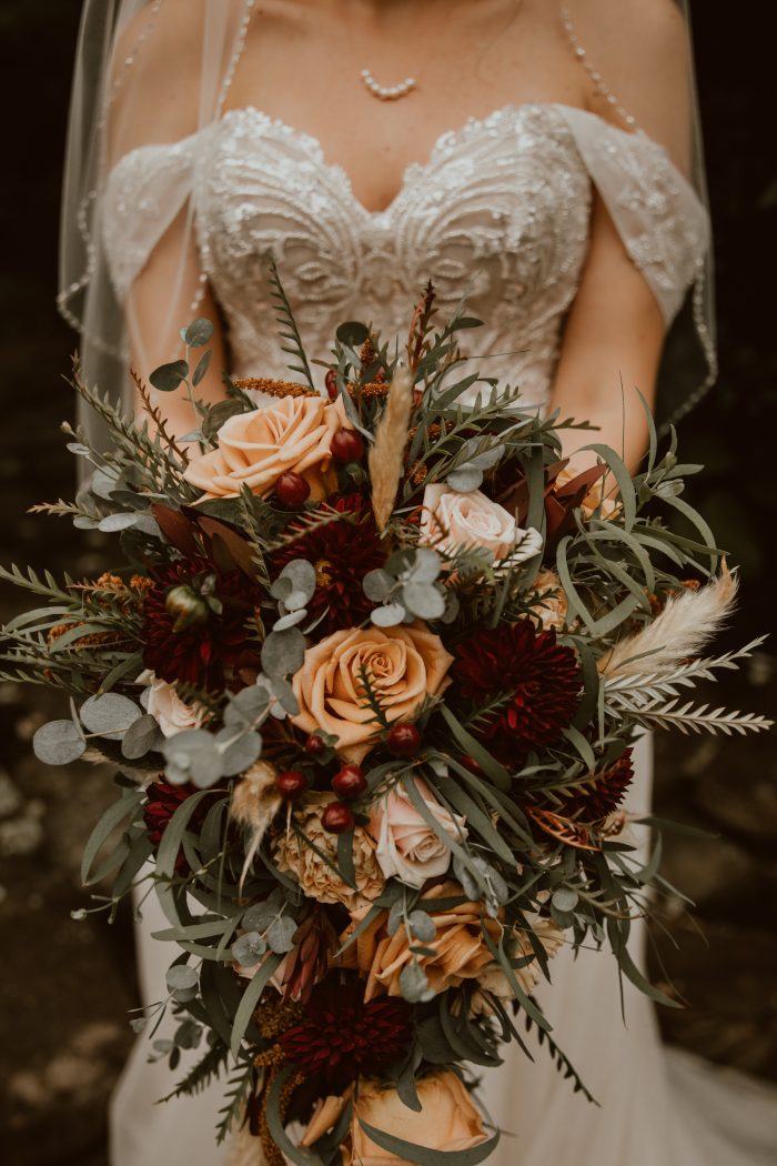 Bride wearing Artemis wedding gown by Maggie Sottero and holding a peach fuzz bouquet