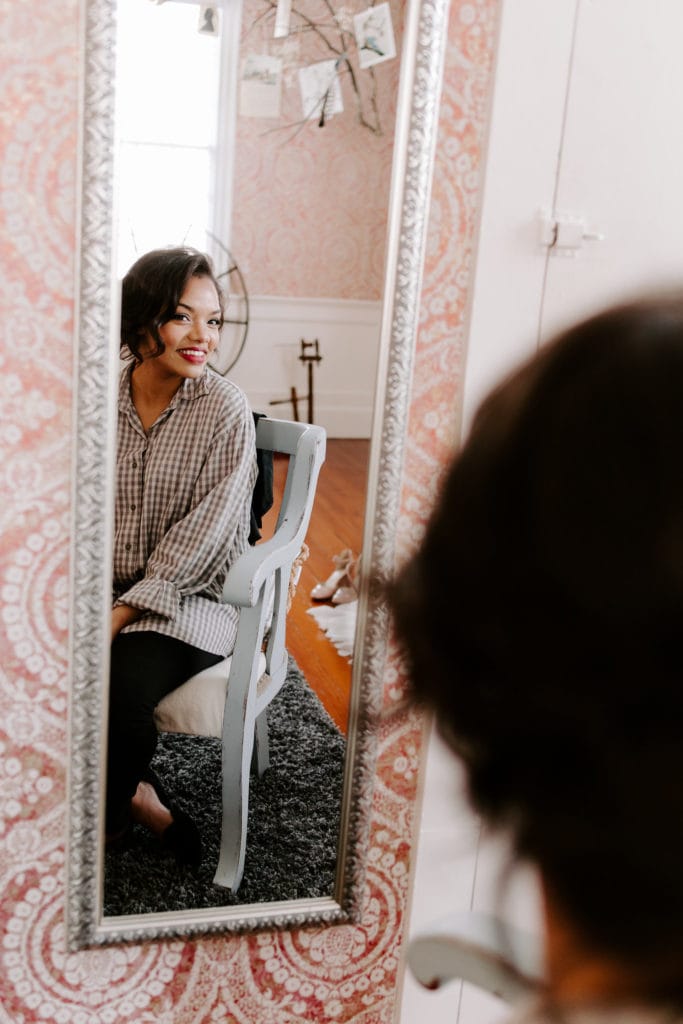 Bride Looking in Mirror and Wearing Wedding Makeup
