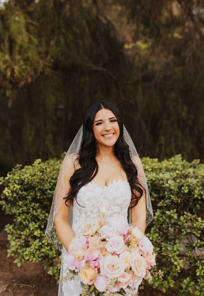 Bride wearing Ivy wedding dress by Maggie Sottero holding a bouquet with the Pantone color of the year 2024 flowers.