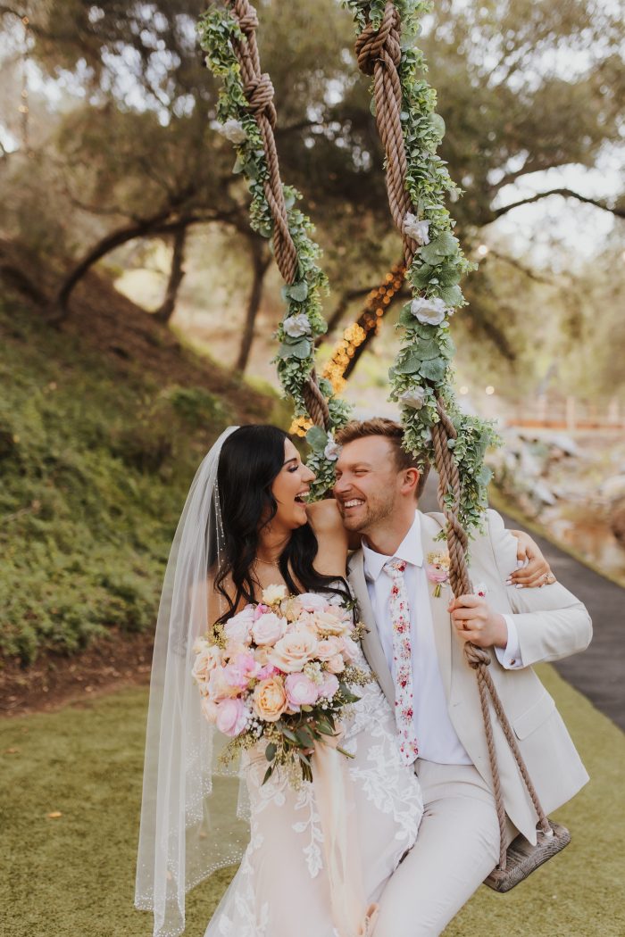 Bride wearing Ivy wedding dress by Maggie Sottero with her husband on a swing