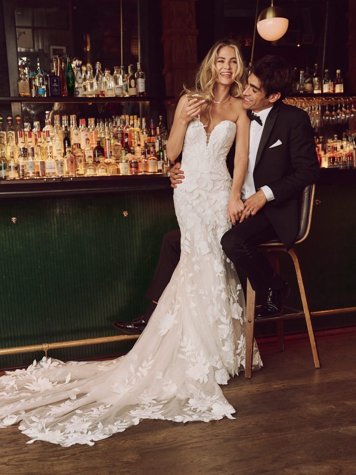 Bride leaning into groom wearing an allover lace wedding dress in a bar