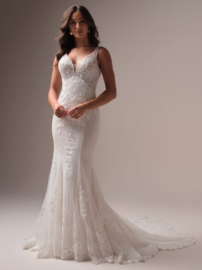 Model wearing the Eloise fit-and-flare wedding dress, featuring a deep V-neckline, illusion lace straps, and allover beaded floral lace that flows into a soft, scalloped train.