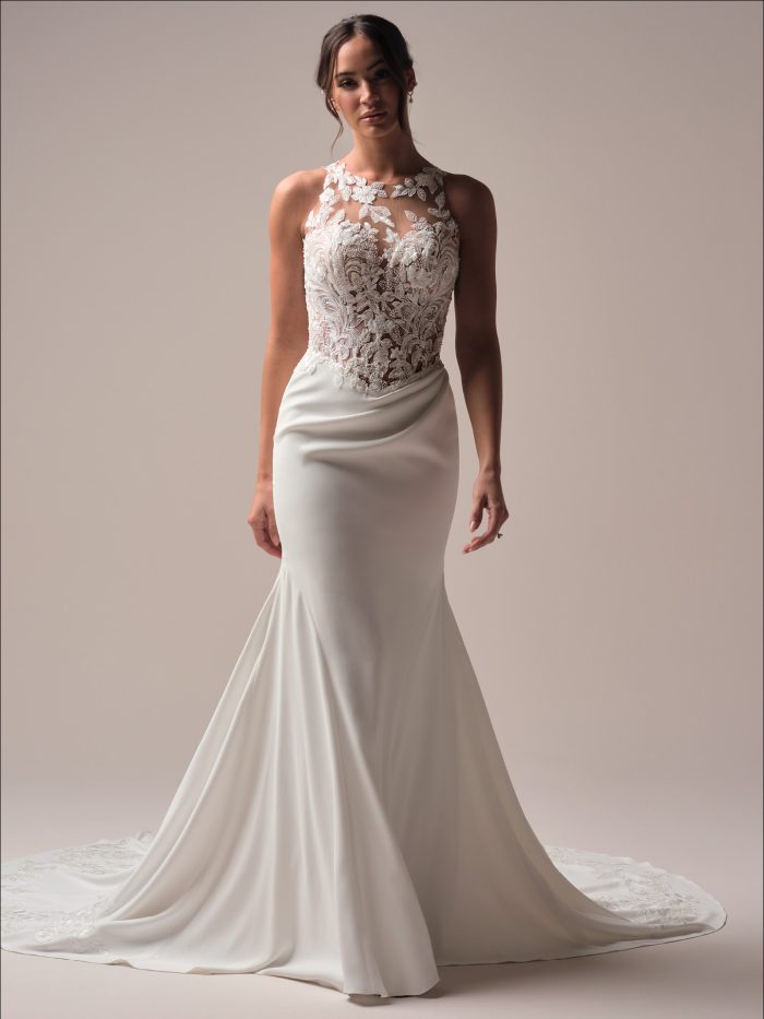 Bride wearing Florentina by Maggie Sottero, a sheath wedding dress with illusion lace halter neckline, embroidered lace bodice, and sleek crepe skirt with chapel train.