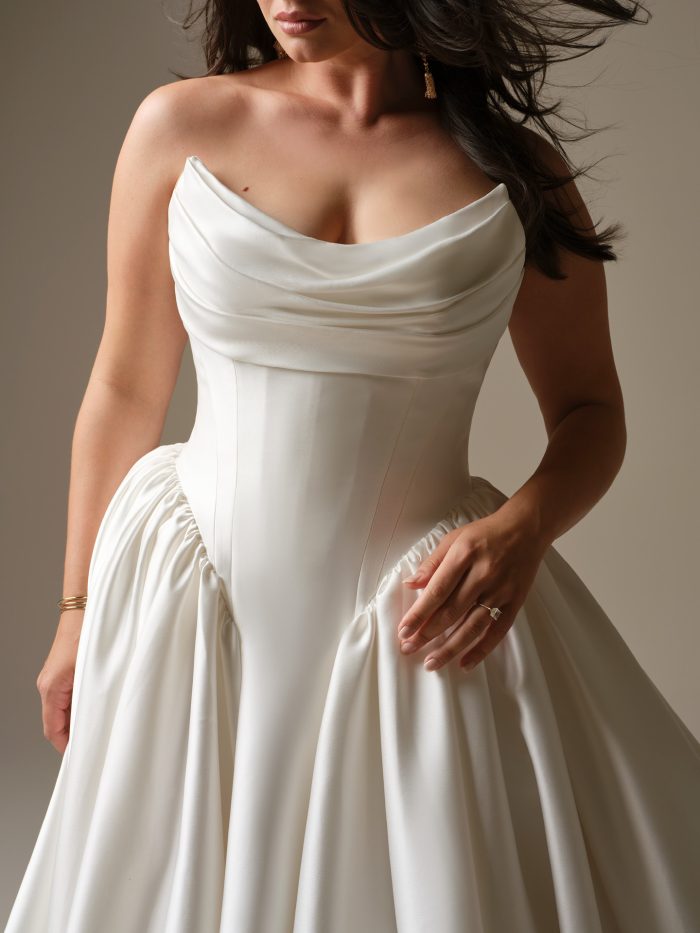 Close-up of the Hudson wedding dress by Maggie Sottero highlighting the draped scoop neckline, corset-style bodice with visible structure, and smooth satin fabric.
