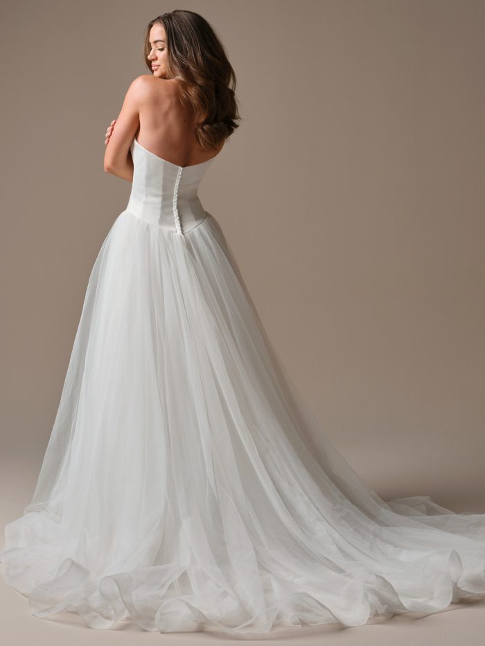 Back view of Shirley by Maggie Sottero — elegant strapless A-line gown with satin bodice, flowing tulle train, and covered buttons down the back.