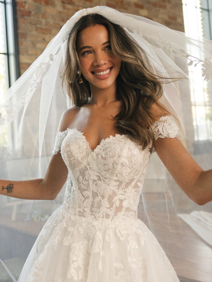 Close-up of the Verina wedding dress by Maggie Sottero showing an illusion beaded lace bodice, sweetheart neckline, and off-the-shoulder cap sleeves