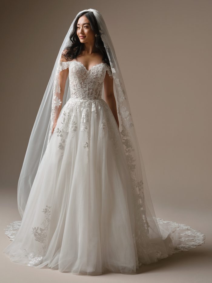 Bride wearing the Verina veil by Maggie Sottero, a cathedral-length mantilla veil with floral lace motifs cascading from head to hem.