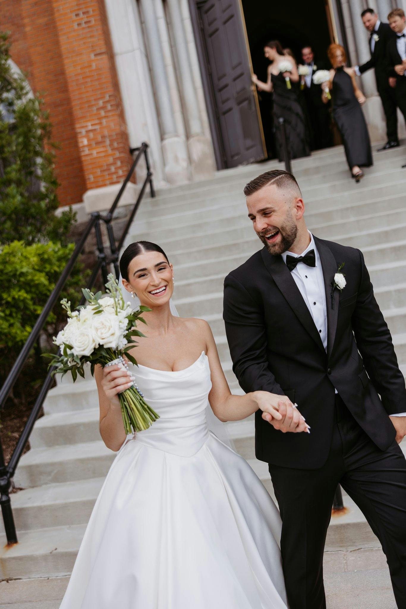 Bride wearing Maureen by Maggie Sottero as she walks with her husband holding hands