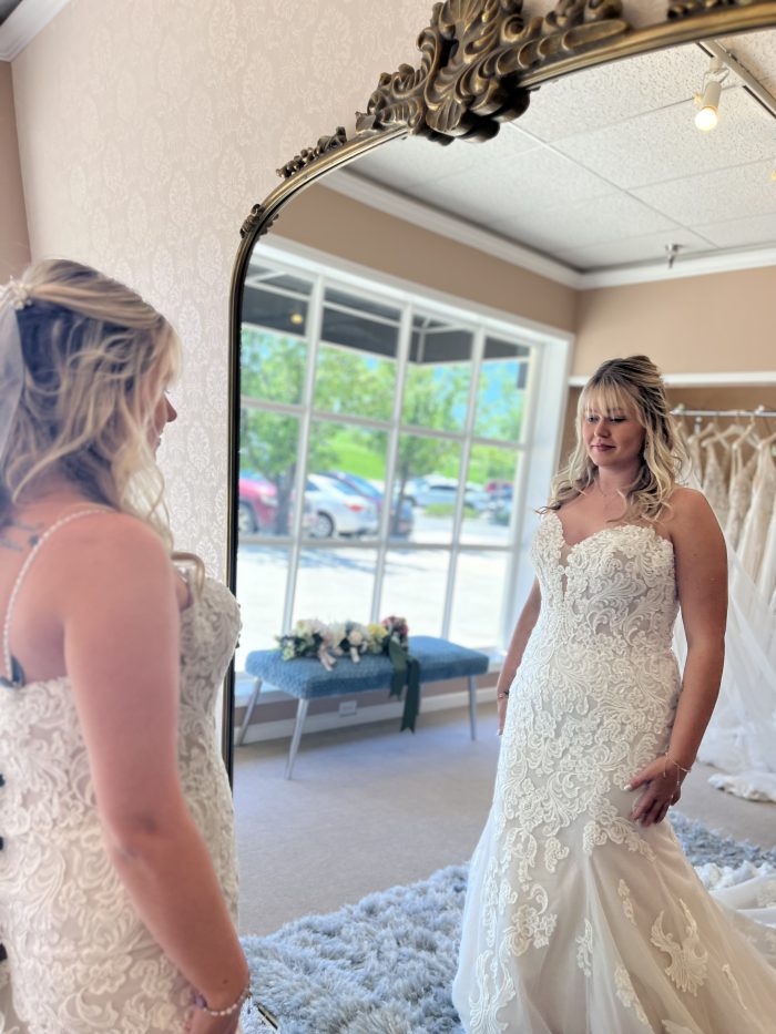 Bride wearing a fit and flare wedding dress looking at herself in the mirror