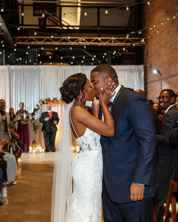 Bride wearing Tuscany Lynette Lace Mermaid wedding dress by Maggie Sottero and Groom kissing at their reception