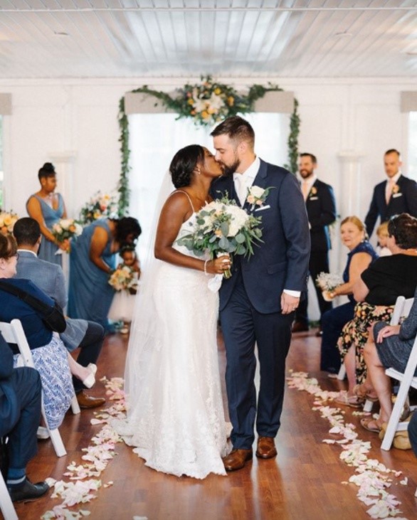 Bride and Groom kissing as they walk down the aisle featuring Nola lace sheath wedding dress by Maggie Sottero