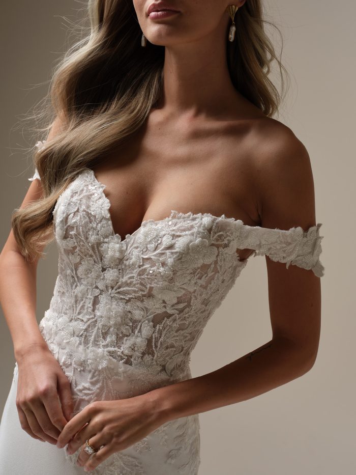 Close-up of the Rebecca Ingram Adeline wedding dress highlighting the off-the-shoulder lace bodice with beaded Chantilly lace and sweetheart neckline.