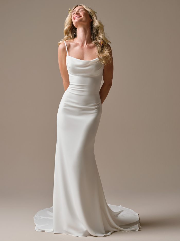 Model wearing the Brenda sheath wedding dress, featuring a delicate cowl neckline, slim spaghetti straps, and a soft crepe silhouette that drapes effortlessly into a minimalist train.
