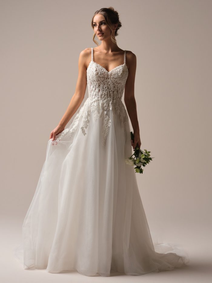 Bride wearing a flowy A-line wedding gown holding a flower bouquet