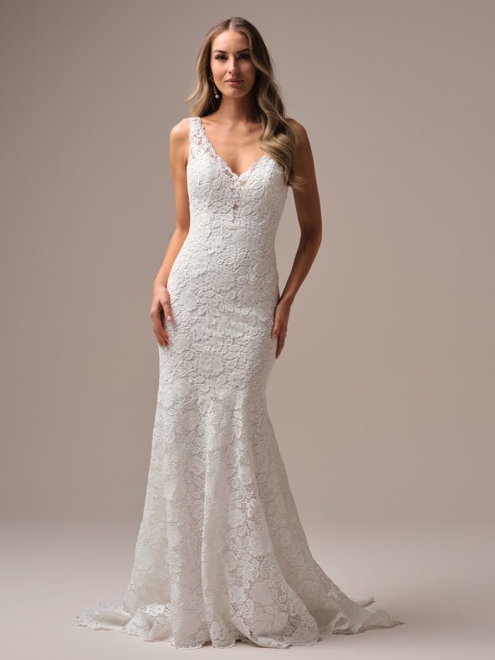 Bride wearing the Dayna sheath wedding dress with allover lace, a plunging V-neckline, and a sleek, vintage-inspired silhouette.