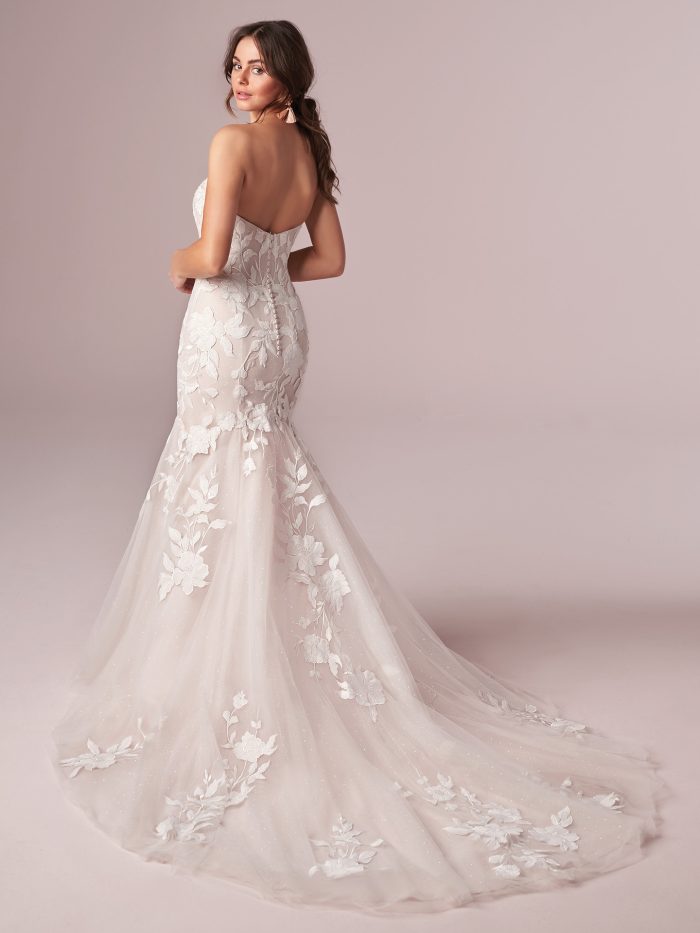 Back view of strapless mermaid wedding dress featuring floral lace appliqués over tulle, illusion detailing, and chapel-length train with delicate floral motifs.