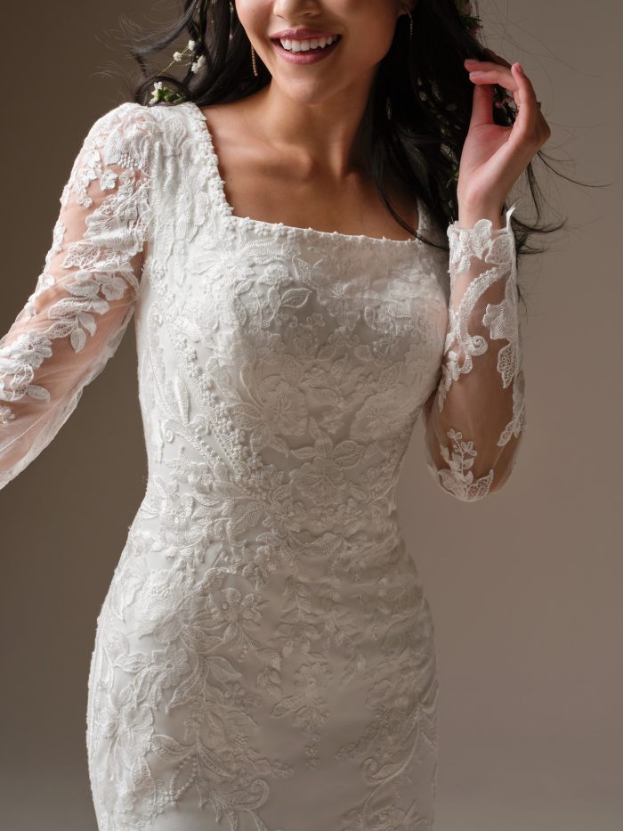 Close-up of Larissa Leigh by Rebecca Ingram, modest square neckline with unembellished lace bodice and fitted illusion lace long sleeves.