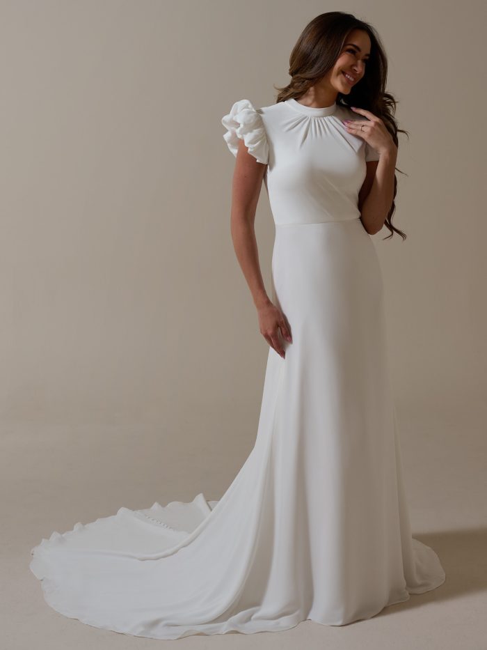 Payson by Rebecca Ingram, simple chiffon A-line wedding dress with high neckline, gathered bodice, ruffled puff sleeves, and covered button back detail.