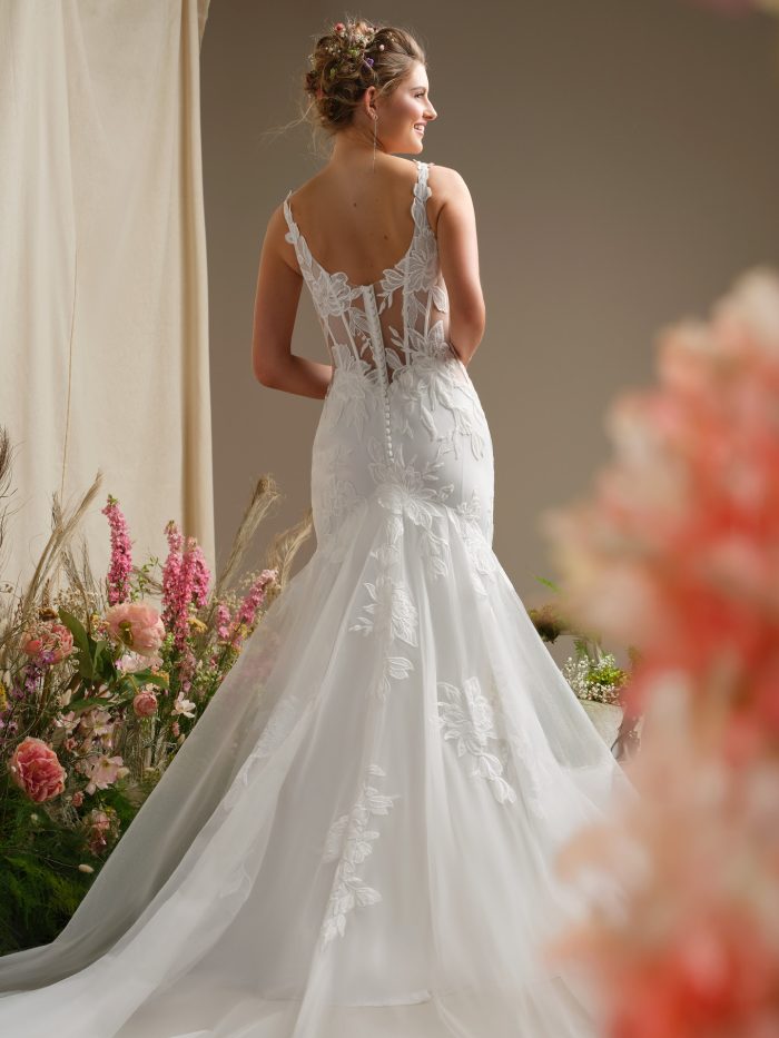 Back view of Rebecca Ingram Pearline wedding dress featuring V-back illusion bodice, lace detailing, covered buttons, and an extended illusion lace train.