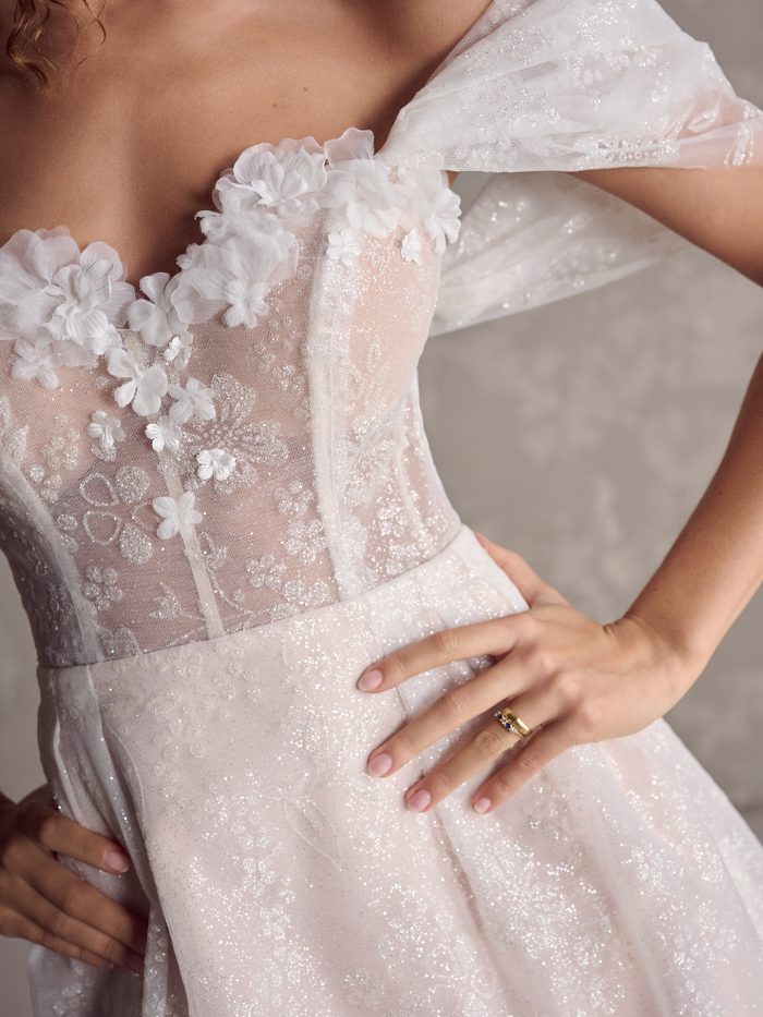 Close up of the Zoe gown showing the 3D floral appliqués, sheer embroidered bodice, and glitter tulle mini skirt with delicate texture and sparkle.