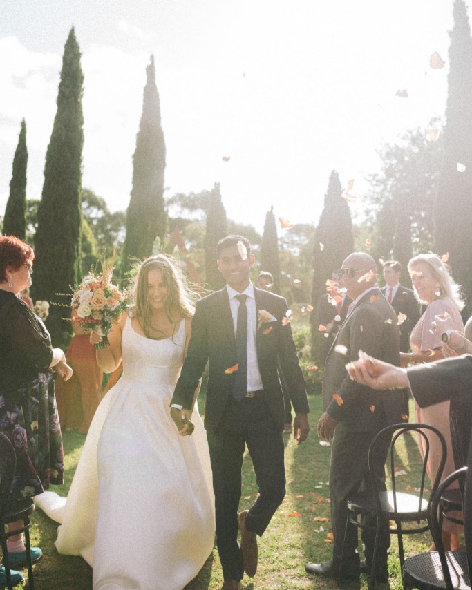 Bride wearing Selena wedding dress by Maggie Sottero walking down the aisle with her husband.