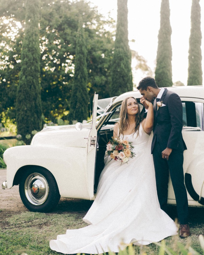 Bride wearing Selena wedding dress by Maggie Sottero holding a bouquet full of flowers in the shade peach fuzz.