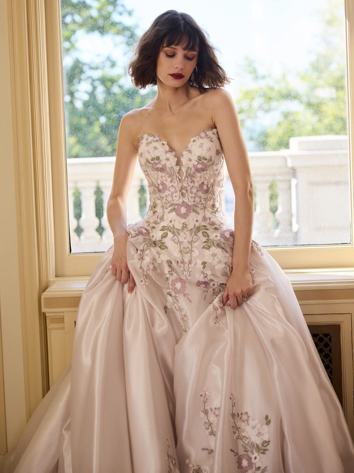 Close-up of the Alvarez wedding dress showing the strapless embroidered bodice with pink and green floral detailing.