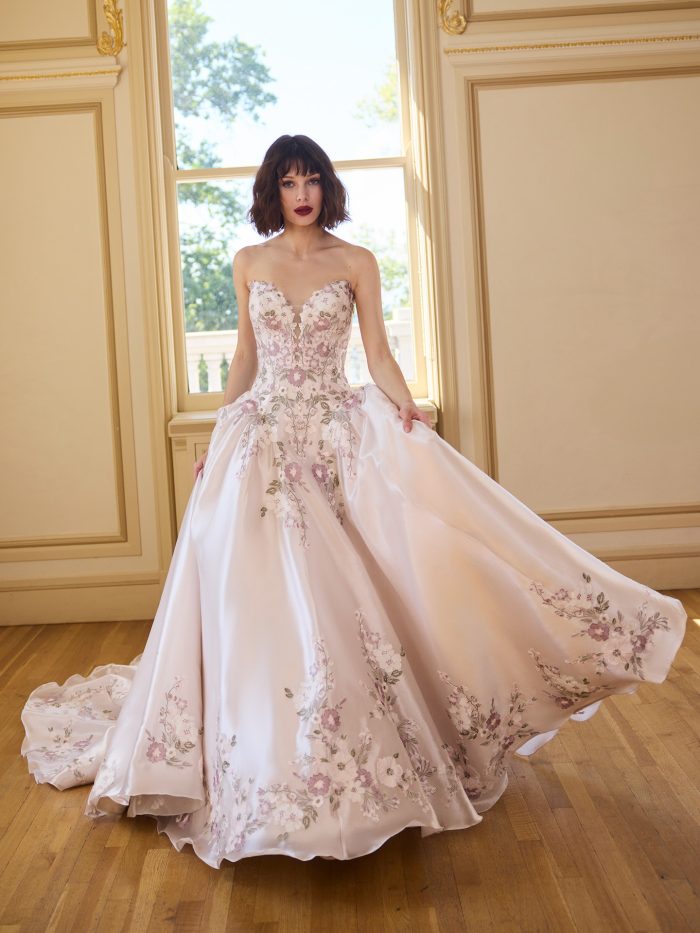 Front view of the Alvarez ballgown wedding dress featuring a strapless embroidered bodice and a full skirt with soft pink floral detailing.