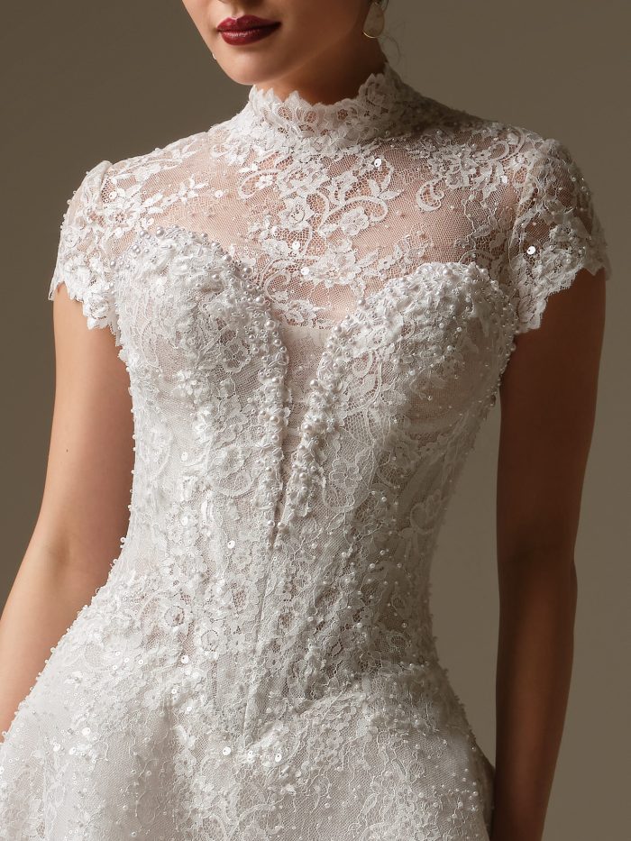 Angelica jacket by Sottero and Midgley, detachable illusion lace bridal jacket featuring mock high neckline, cap sleeves, and beaded lace embroidery over sweetheart bodice.