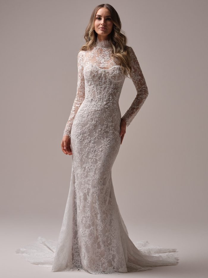 Bride wearing the Jovienne wedding dress with the long sleeve lace jacket, featuring an illusion high neckline, fitted lace silhouette, and scalloped train.