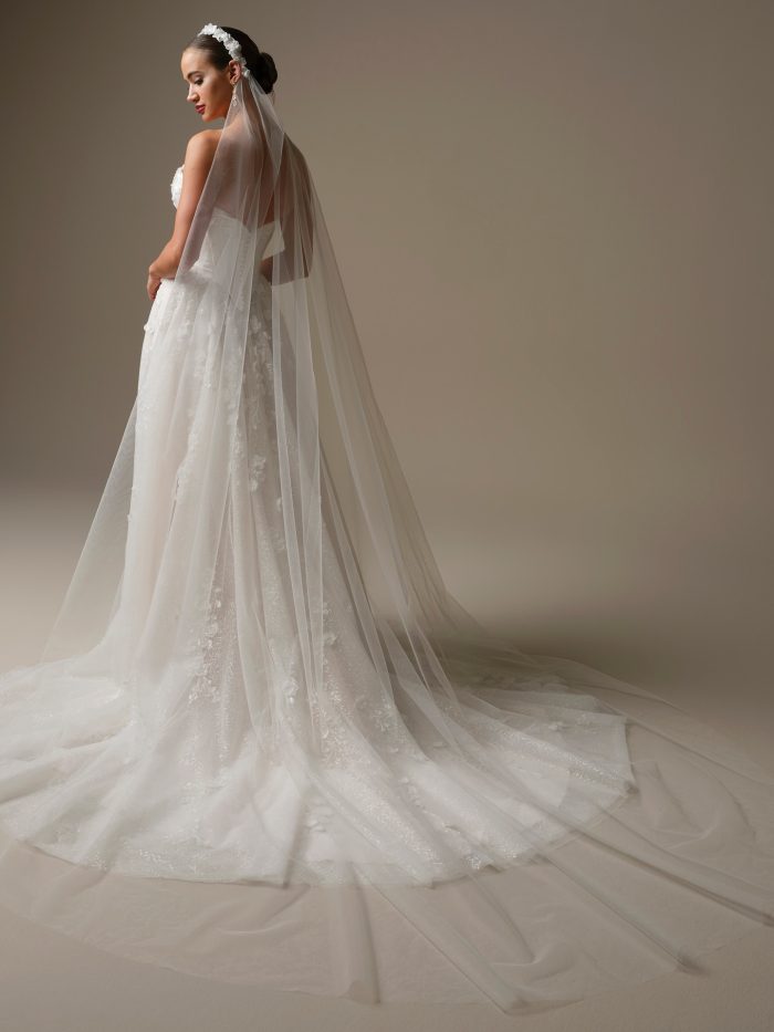 Back view of the Kalinda veil by Sottero and Midgley, showcasing its cathedral-length tulle, delicate floral headband, and romantic trailing silhouette over a lace gown.