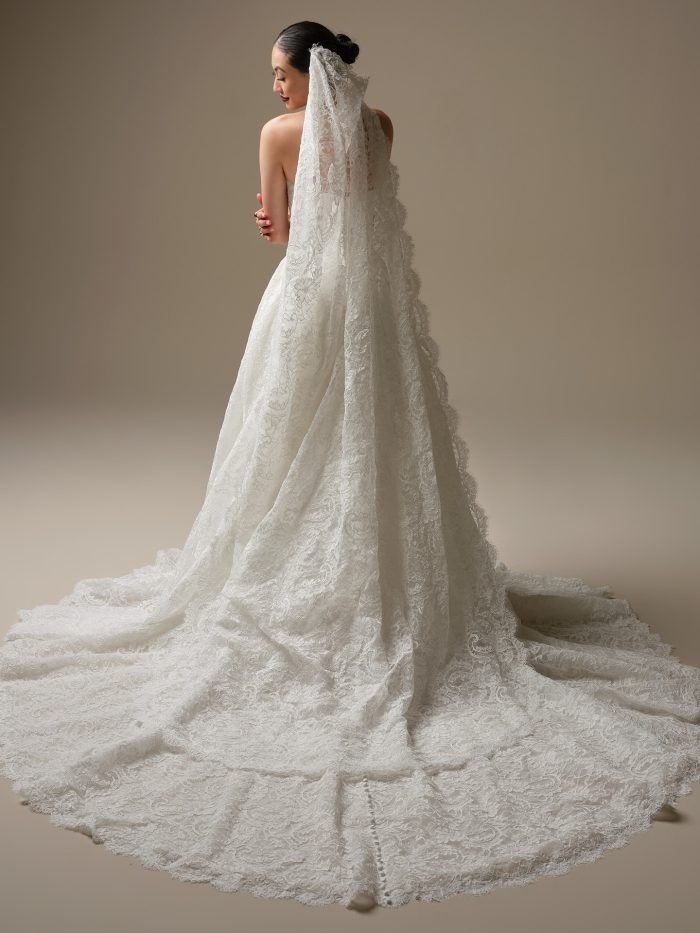 Bride wearing the Tamar veil by Sottero and Midgley, a royal-length mantilla veil with allover lace and scalloped edging flowing into a dramatic train.