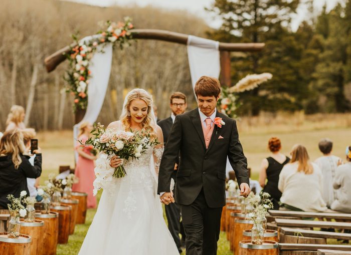 Bride wearing Stevie wedding dress by Maggie Sottero and holding her husband's hand.