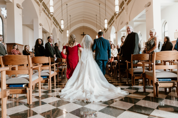Michelle walking down the aisle with her father and the mother of the bride in Kalina by Rebecca Ingram
