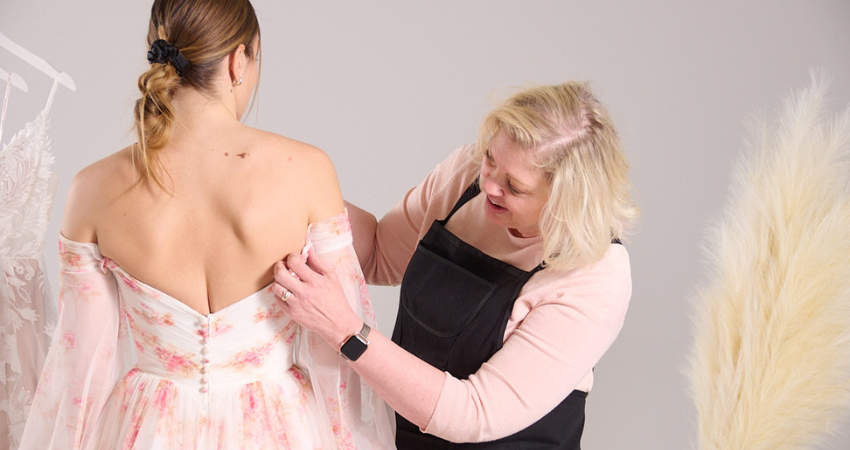 Seamstress performing wedding dress alterations on a bride