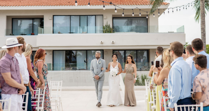 Bride being walked down the aisle by both her parents, a fun twist on wedding traditions