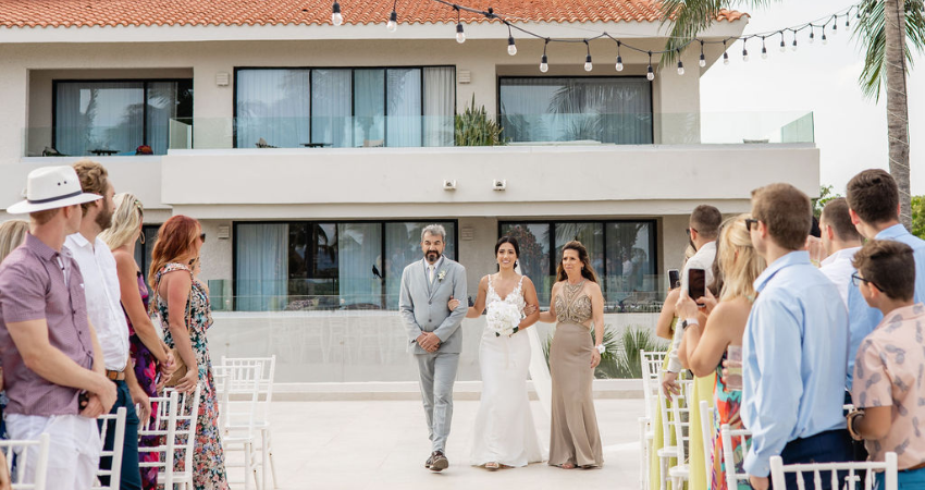 Bride being walked down the aisle by both her parents, a fun twist on wedding traditions